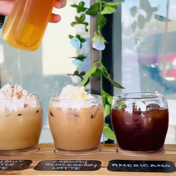 Honey drizzled over three iced coffee drinks, including a creamy blackberry latte and an Americano.