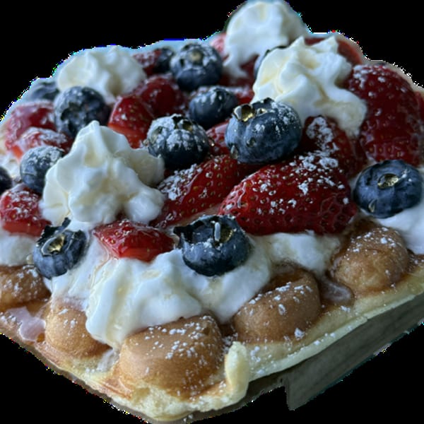 Bubble waffle topped with fresh strawberries, blueberries, whipped cream, and powdered sugar.