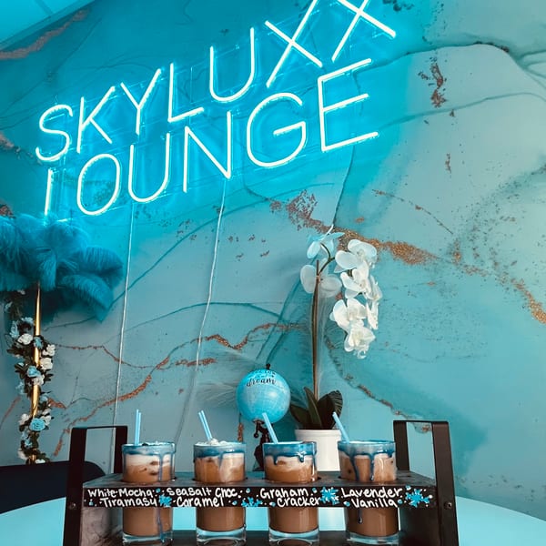 Skyluxx Lounge neon sign above a display of mini dessert shots against a blue and gold wall.