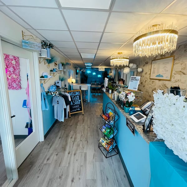 A long, narrow room with light blue walls, light wood floors, and a counter with snacks and drinks.